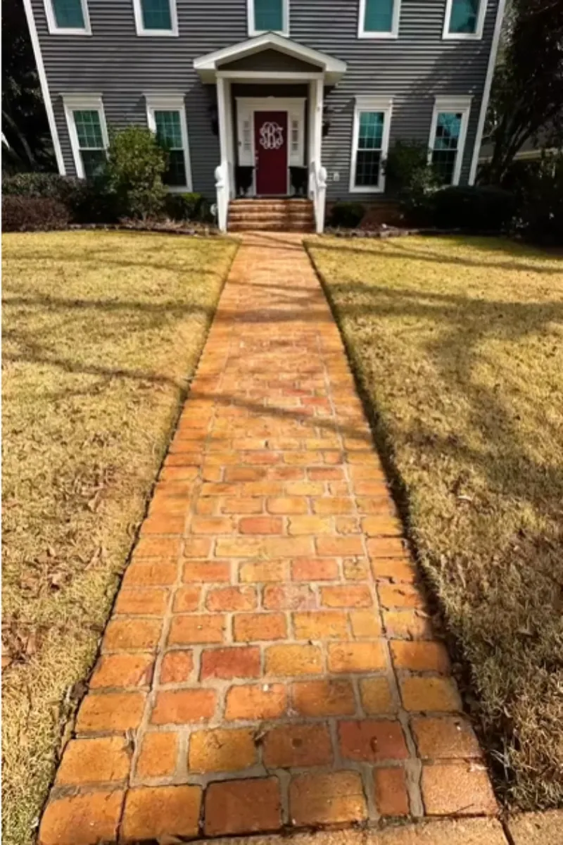 Dirty brick walkway with algae staining leading to a home's front entrance before pressure washing in Asheville, NC