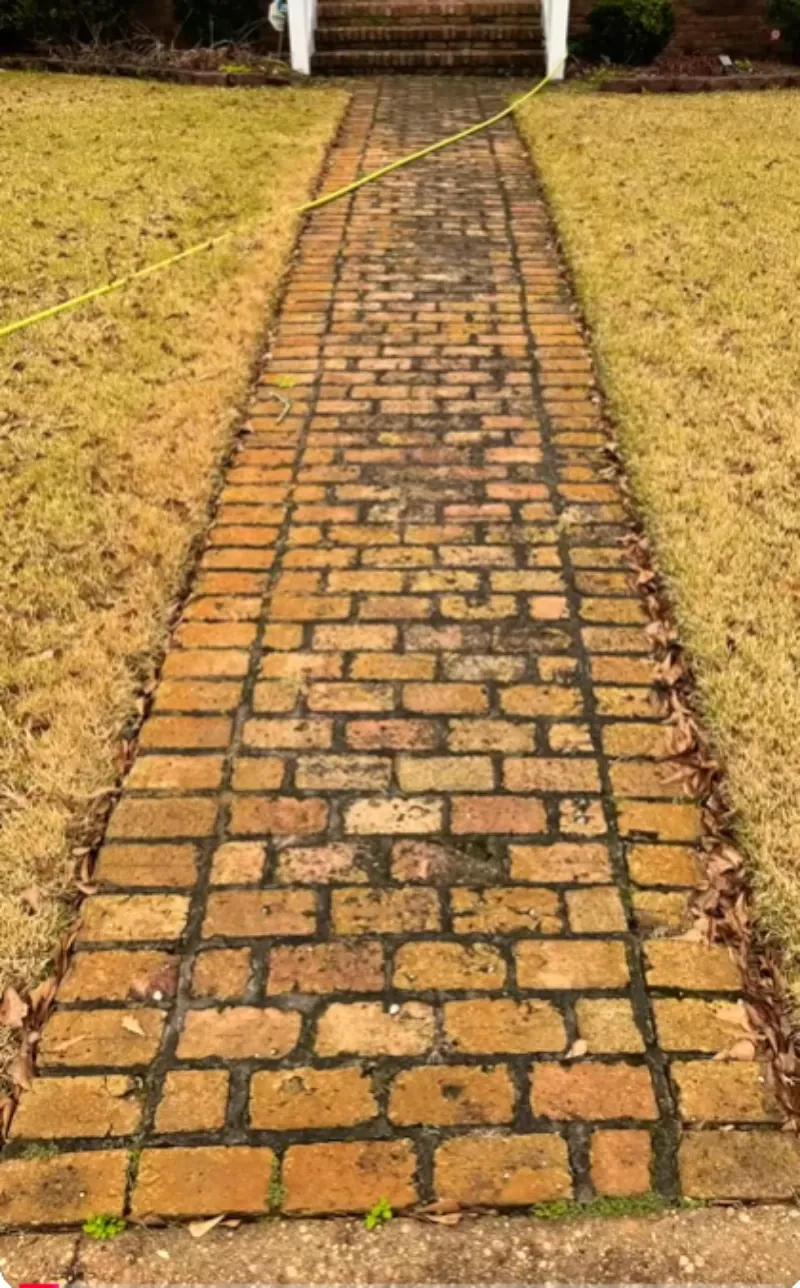 Brick walkway mid-cleaning, showing the clear line between pressure-washed and untreated brick