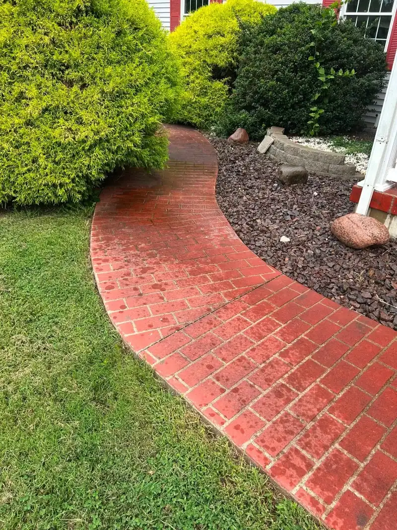 Same curved brick walkway after pressure washing, with the vibrant red brick color fully restored
